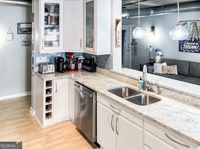 800 Peachtree St NE Unit 1319, Atlanta, GA 30308 - kitchen with stainless steel dishwasher, light wood-style flooring, white cabinetry, backsplash, and light stone counters