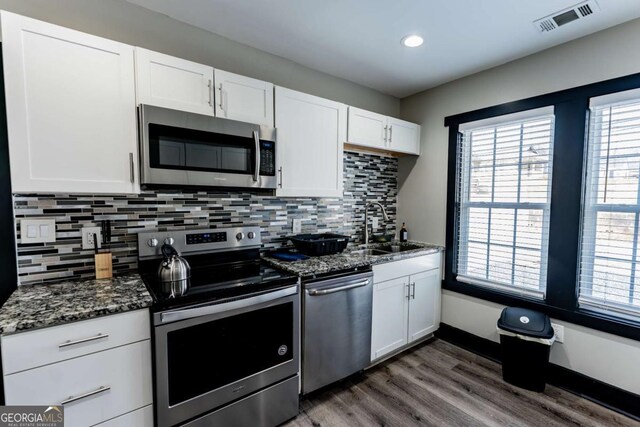 1764 Spring Ave, East Point, GA 30344 - kitchen with stainless steel appliances, dark wood finished floors, white cabinetry, dark stone countertops, and tasteful backsplash
