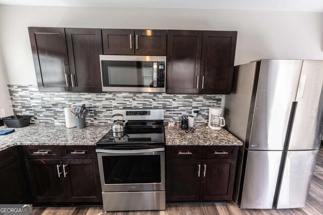 1764 Spring Ave, East Point, GA 30344 - kitchen with stainless steel appliances, dark brown cabinetry, decorative backsplash, light stone countertops, and light wood-style floors