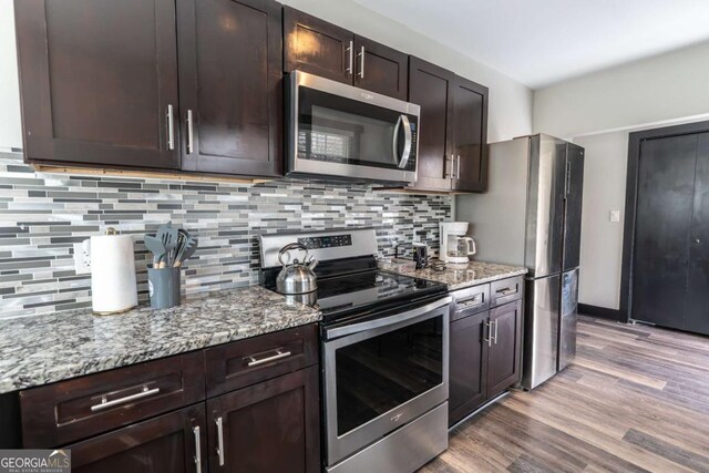 1764 Spring Ave, East Point, GA 30344 - kitchen with appliances with stainless steel finishes, dark brown cabinets, light wood-style flooring, and decorative backsplash