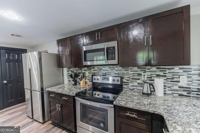 1764 Spring Ave, East Point, GA 30344 - kitchen featuring stainless steel appliances, dark brown cabinets, light wood-type flooring, light stone countertops, and decorative backsplash