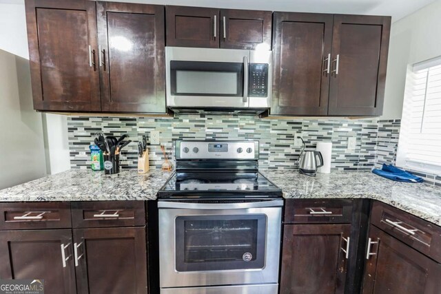 1764 Spring Ave, East Point, GA 30344 - kitchen featuring appliances with stainless steel finishes, dark brown cabinetry, decorative backsplash, and light stone countertops