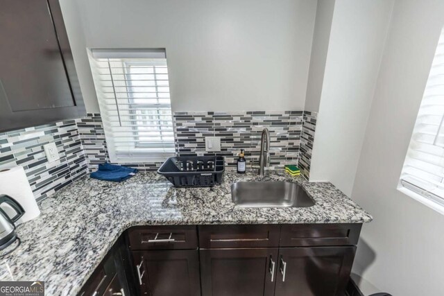 1764 Spring Ave, East Point, GA 30344 - kitchen featuring dark brown cabinets, decorative backsplash, healthy amount of natural light, and light stone counters