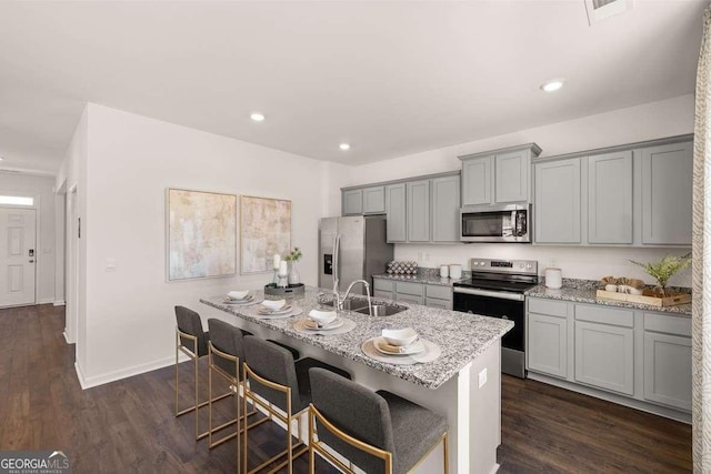 170 Aster Ave, Locust Grove, GA 30248 - kitchen featuring appliances with stainless steel finishes, gray cabinets, a sink, light stone countertops, and a kitchen breakfast bar