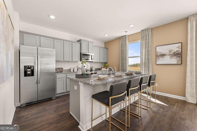 170 Aster Ave, Locust Grove, GA 30248 - kitchen with appliances with stainless steel finishes, gray cabinets, a breakfast bar, baseboards, and dark wood-type flooring