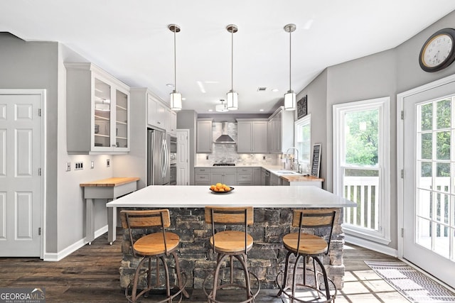 4527 Village Springs Run, Dunwoody, GA 30338 - kitchen featuring wall chimney exhaust hood, gray cabinetry, dark wood finished floors, appliances with stainless steel finishes, and light countertops