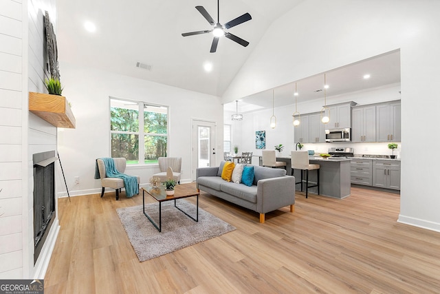 8544 Plumtree Dr, Riverdale, GA 30274 - living room featuring light wood-style floors, ceiling fan, high vaulted ceiling, a large fireplace, and baseboards
