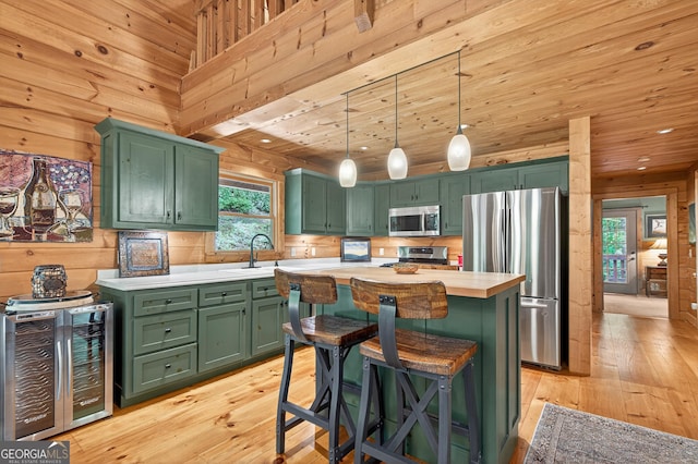 744 Dover Falls Trl, Ellijay, GA 30540 - kitchen with green cabinetry, stainless steel appliances, wine cooler, light countertops, and wooden walls