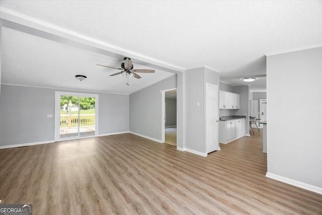 165 Forest Hill Dr, Eatonton, GA 31024 - unfurnished living room with ceiling fan, ornamental molding, light wood-type flooring, a textured ceiling, and baseboards