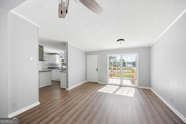 165 Forest Hill Dr, Eatonton, GA 31024 - unfurnished living room featuring dark wood-type flooring, crown molding, baseboards, ceiling fan, and a textured ceiling
