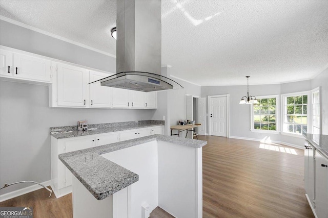 165 Forest Hill Dr, Eatonton, GA 31024 - kitchen featuring island exhaust hood, a textured ceiling, wood finished floors, white cabinetry, and a kitchen island