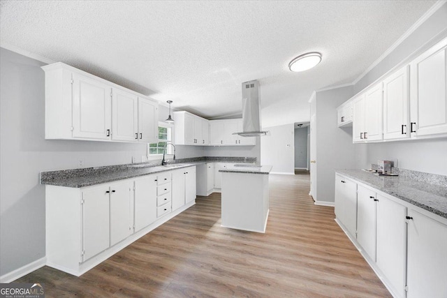 165 Forest Hill Dr, Eatonton, GA 31024 - kitchen with island exhaust hood, a textured ceiling, white cabinetry, baseboards, and a sink