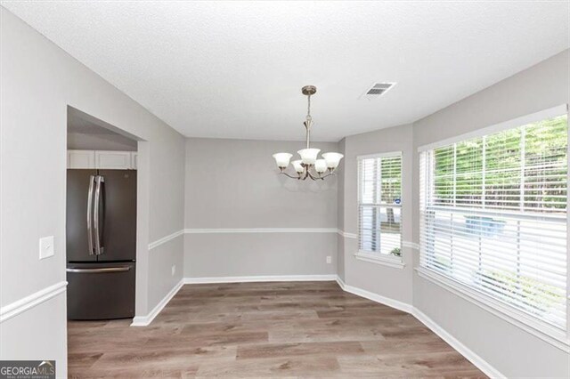 11827 Spring Lake Way, Fayetteville, GA 30215 - unfurnished dining area with a chandelier, light wood finished floors, and baseboards