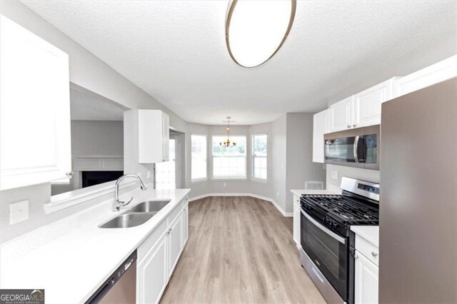 11827 Spring Lake Way, Fayetteville, GA 30215 - kitchen with appliances with stainless steel finishes, a sink, white cabinets, light countertops, and a textured ceiling