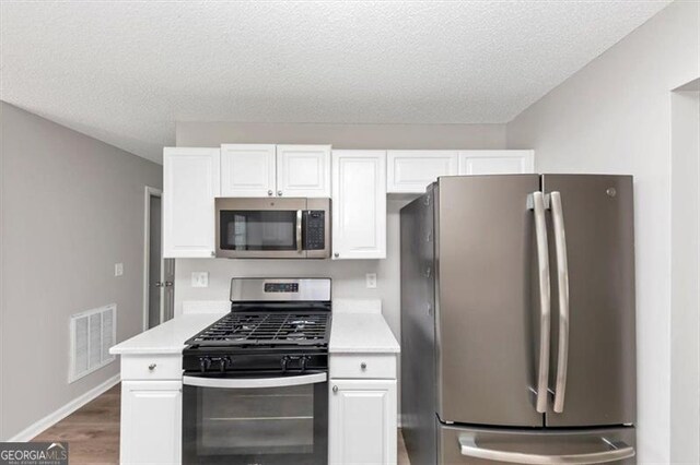 11827 Spring Lake Way, Fayetteville, GA 30215 - kitchen featuring appliances with stainless steel finishes, light countertops, white cabinets, wood finished floors, and a textured ceiling