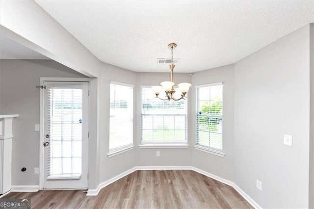 11827 Spring Lake Way, Fayetteville, GA 30215 - unfurnished dining area with a chandelier, wood finished floors, baseboards, and a textured ceiling