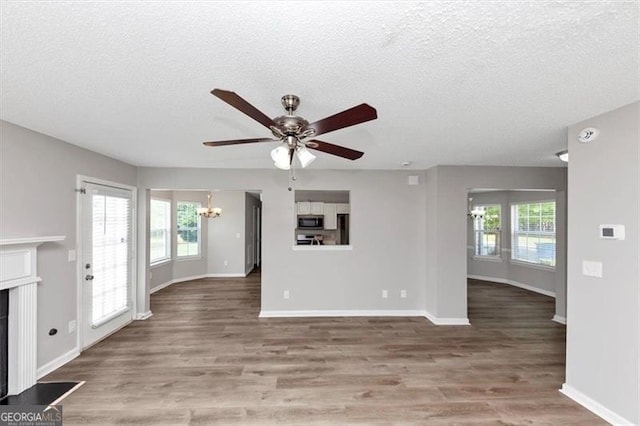 11827 Spring Lake Way, Fayetteville, GA 30215 - unfurnished living room with a chandelier, a ceiling fan, a fireplace with flush hearth, wood finished floors, and a textured ceiling