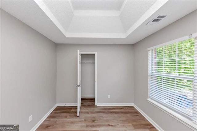 11827 Spring Lake Way, Fayetteville, GA 30215 - unfurnished bedroom featuring a raised ceiling, light wood-type flooring, a walk in closet, a closet, and baseboards