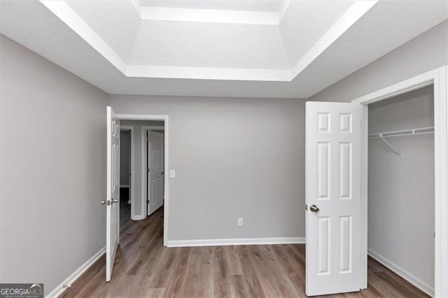 11827 Spring Lake Way, Fayetteville, GA 30215 - unfurnished bedroom with wood finished floors, baseboards, a tray ceiling, and a closet