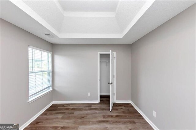 11827 Spring Lake Way, Fayetteville, GA 30215 - unfurnished bedroom with a tray ceiling, wood finished floors, a walk in closet, baseboards, and a closet