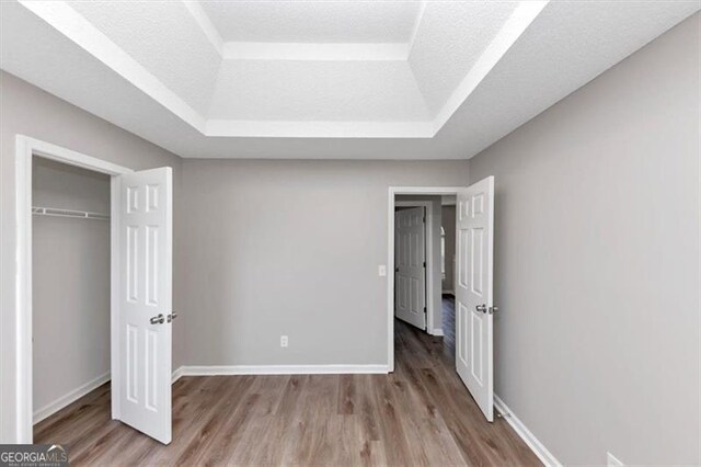 11827 Spring Lake Way, Fayetteville, GA 30215 - unfurnished bedroom featuring a tray ceiling, wood finished floors, baseboards, and a closet