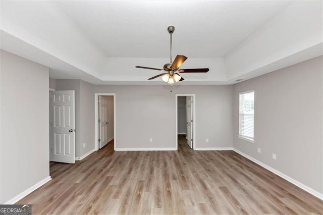 11827 Spring Lake Way, Fayetteville, GA 30215 - unfurnished bedroom with a tray ceiling, wood finished floors, baseboards, a walk in closet, and a ceiling fan