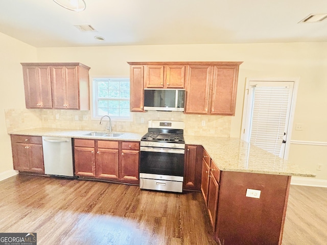 759 Hennepin Ter, Mcdonough, GA 30253 - kitchen featuring stainless steel appliances, a peninsula, a sink, wood finished floors, and light stone countertops