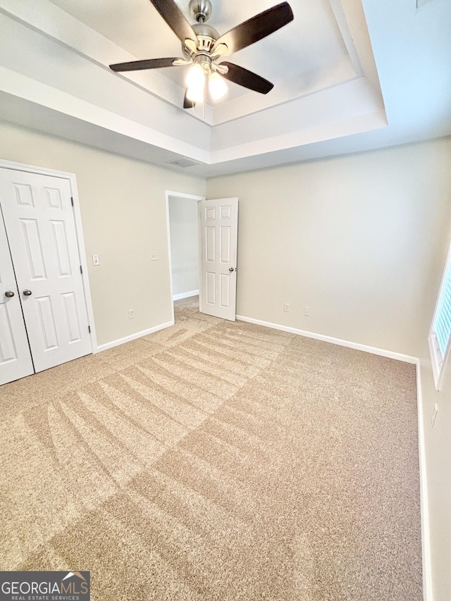 759 Hennepin Ter, Mcdonough, GA 30253 - unfurnished bedroom featuring a tray ceiling, baseboards, carpet flooring, and ceiling fan