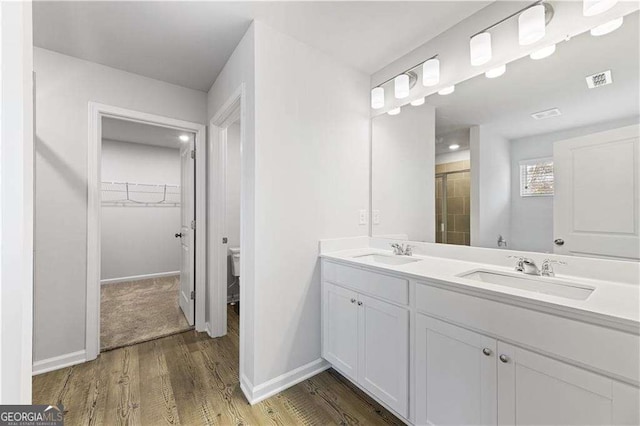 7193 Brushwood Bnd, Lithonia, GA 30058 - bathroom with toilet, double vanity, a walk in closet, wood finished floors, and a shower