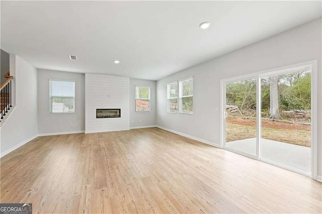 7193 Brushwood Bnd, Lithonia, GA 30058 - unfurnished living room featuring plenty of natural light, light wood finished floors, stairway, baseboards, and recessed lighting