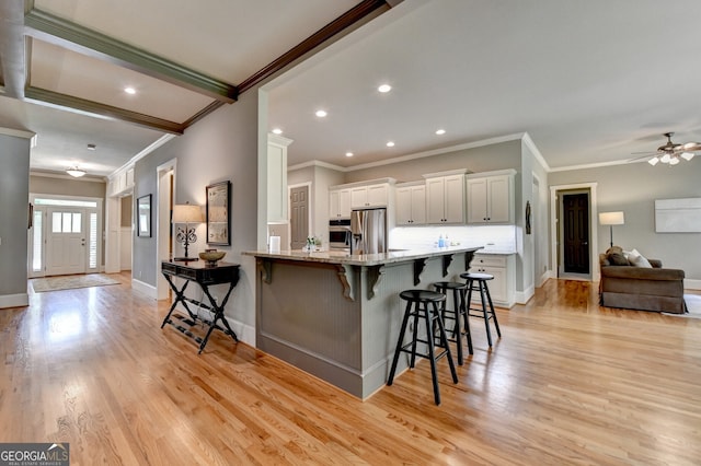 3715 Horizon Ct, Cumming, GA 30041 - kitchen with crown molding, a kitchen bar, light stone countertops, light wood finished floors, and stainless steel appliances