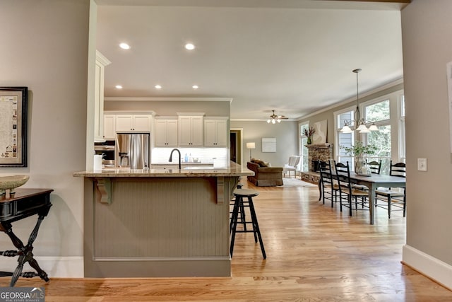 3715 Horizon Ct, Cumming, GA 30041 - kitchen featuring stainless steel appliances, ornamental molding, a fireplace, a breakfast bar, and white cabinetry