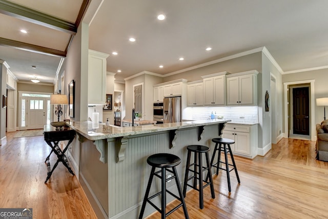3715 Horizon Ct, Cumming, GA 30041 - kitchen featuring crown molding, a peninsula, light stone countertops, light wood-style flooring, and a breakfast bar