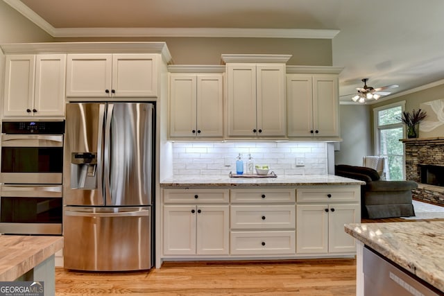 3715 Horizon Ct, Cumming, GA 30041 - kitchen featuring stainless steel appliances, crown molding, light wood-style flooring, backsplash, and white cabinets