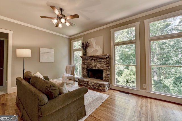 3715 Horizon Ct, Cumming, GA 30041 - living room featuring light wood-style floors, ceiling fan, healthy amount of natural light, a stone fireplace, and crown molding