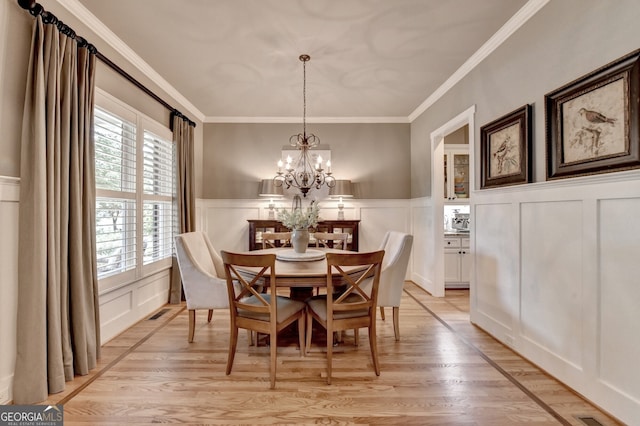 3715 Horizon Ct, Cumming, GA 30041 - dining area featuring a decorative wall, light wood finished floors, a wainscoted wall, a chandelier, and ornamental molding