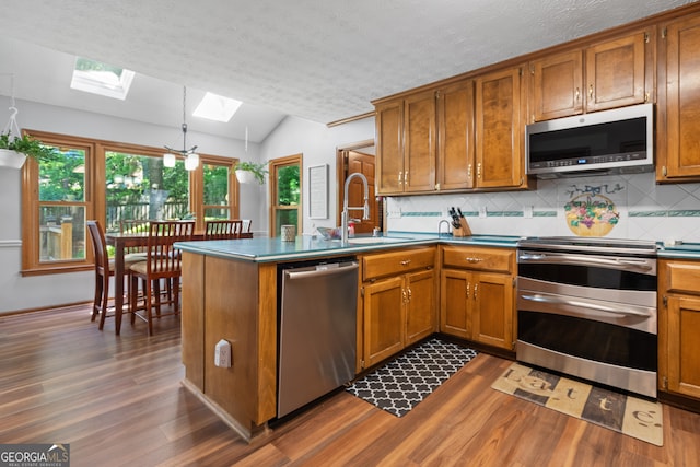 1850 Linnet Ct NE, Roswell, GA 30075 - kitchen featuring appliances with stainless steel finishes, a skylight, dark wood-style flooring, brown cabinetry, and lofted ceiling