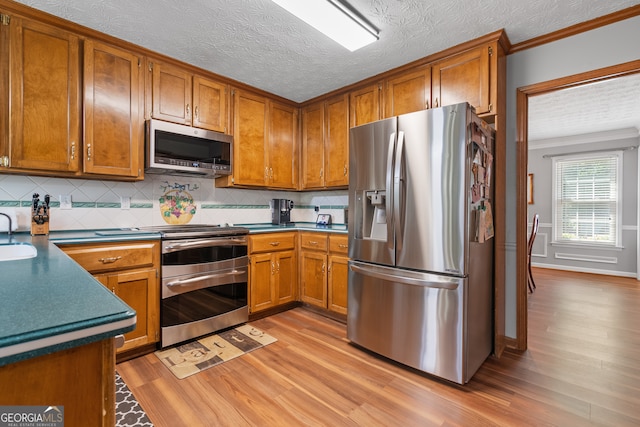 1850 Linnet Ct NE, Roswell, GA 30075 - kitchen with stainless steel appliances, light wood-style floors, brown cabinetry, decorative backsplash, and dark countertops