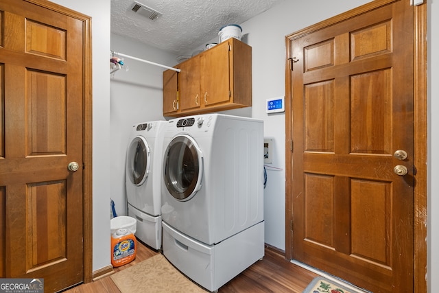1850 Linnet Ct NE, Roswell, GA 30075 - laundry area with wood finished floors, washer and clothes dryer, a textured ceiling, cabinet space, and baseboards