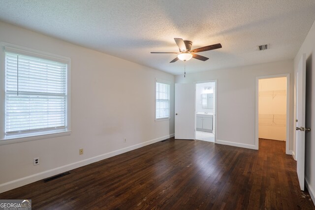 215 E Main St, Hahira, GA 31632 - unfurnished bedroom with wood finished floors, a walk in closet, a textured ceiling, baseboards, and connected bathroom