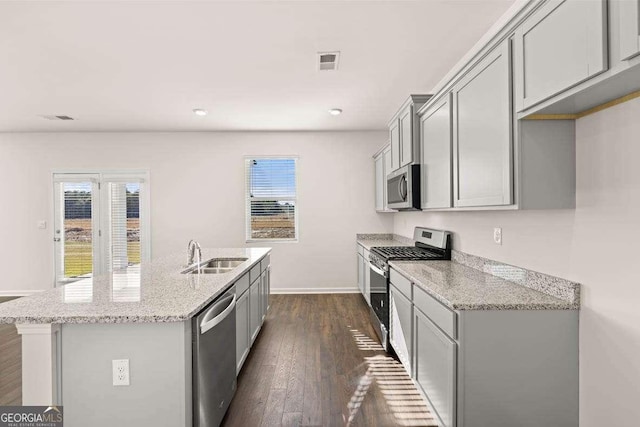 173 Aster Ave, Locust Grove, GA 30248 - kitchen featuring appliances with stainless steel finishes, a sink, gray cabinetry, an island with sink, and light stone countertops