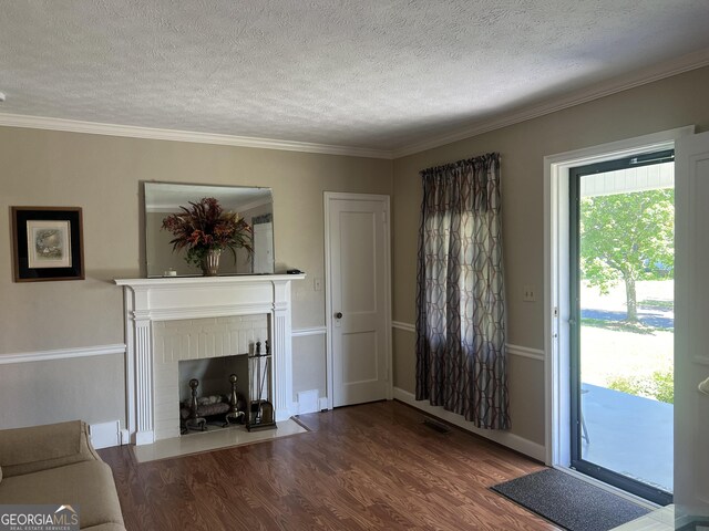 608 4th Ave SW, Thomaston, GA 30286 - unfurnished living room featuring a textured ceiling, wood finished floors, ornamental molding, and a fireplace