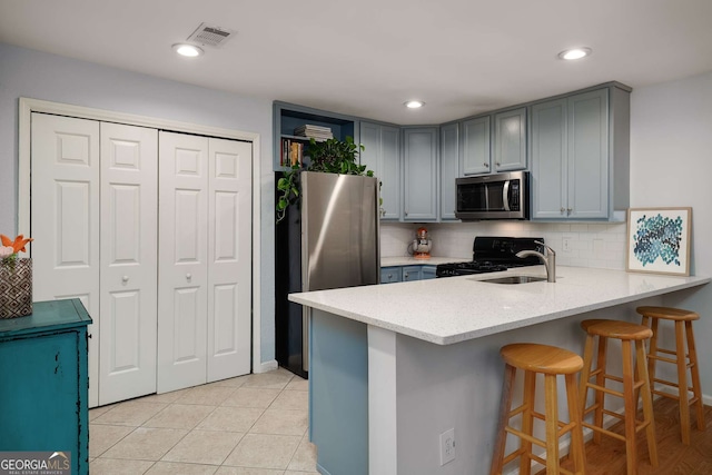 1445 Monroe Dr NE Unit C13, Atlanta, GA 30324 - kitchen featuring stainless steel appliances, a peninsula, tasteful backsplash, a kitchen bar, and gray cabinets