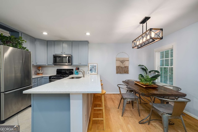 1445 Monroe Dr NE Unit C13, Atlanta, GA 30324 - kitchen with stainless steel appliances, gray cabinets, a peninsula, light stone counters, and decorative light fixtures