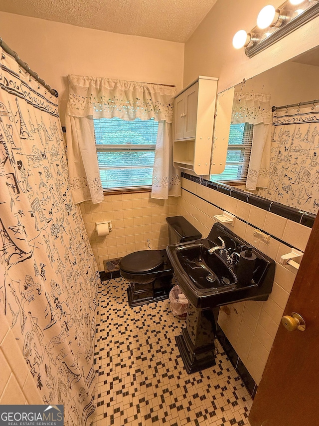 5141 Hiram Lithia Springs Rd, Powder Springs, GA 30127 - bathroom with tile walls, toilet, a wainscoted wall, tile patterned floors, and a textured ceiling