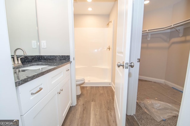 628 Grove St, Barnesville, GA 30204 - bathroom featuring toilet, vanity, wood finished floors, a spacious closet, and a shower