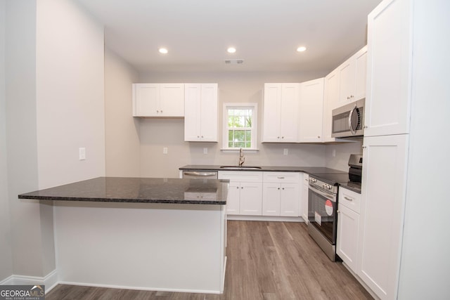 628 Grove St, Barnesville, GA 30204 - kitchen with appliances with stainless steel finishes, light wood-style floors, a sink, dark stone countertops, and white cabinets