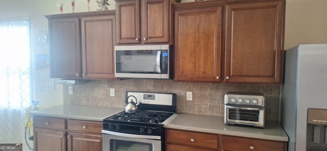 7314 Basalt Dr, Union City, GA 30291 - kitchen featuring appliances with stainless steel finishes, light countertops, backsplash, and brown cabinets