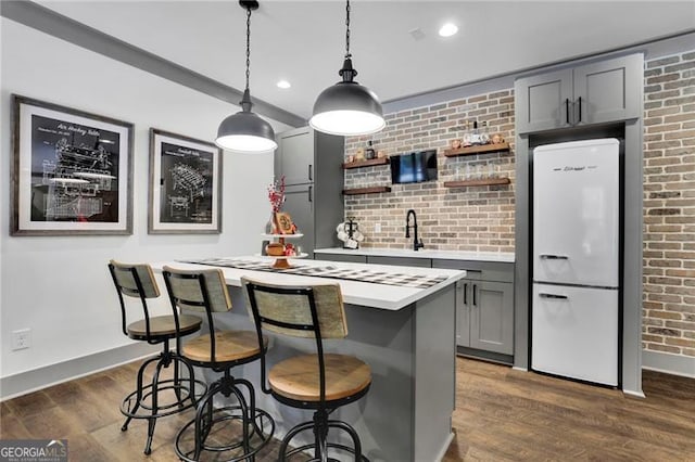 3330 Riverwalk Way, Cumming, GA 30040 - kitchen with freestanding refrigerator, baseboards, light countertops, brick wall, and a center island
