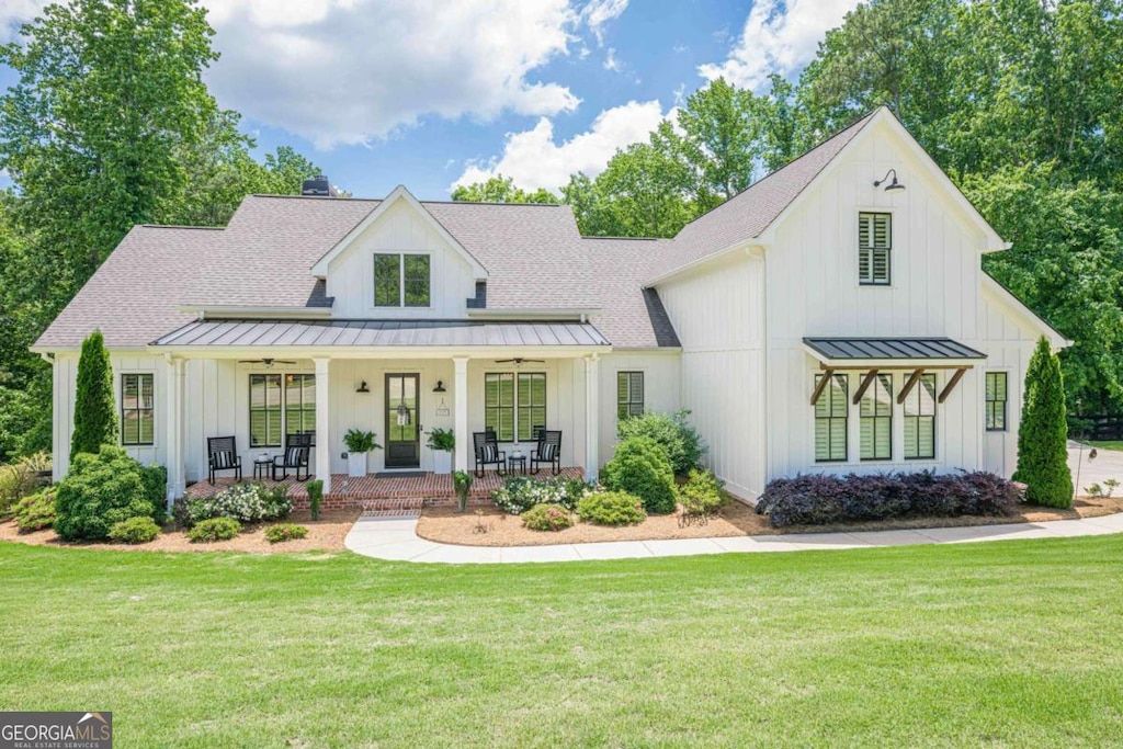 124 White Oak Trl, Cumming, GA 30028 - modern inspired farmhouse featuring a standing seam roof, a porch, board and batten siding, metal roof, and a front lawn